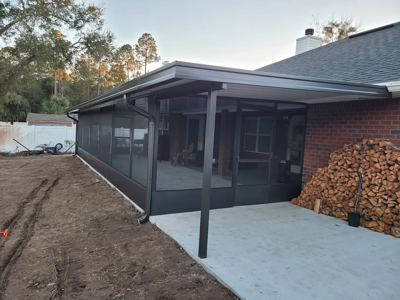 Dark aluminum screened enclosure attached to a brick home